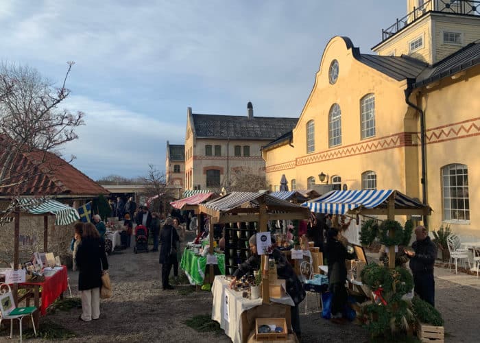 Gula äldre byggnader i betong, julmarknad utomhus med marknadsstånd med randiga tak